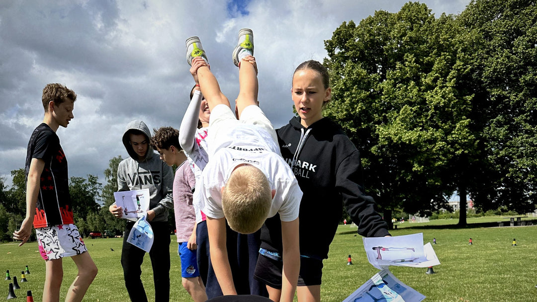 Young camp player flipped upside down in a team balance exercise on the grass at ZWISH camp