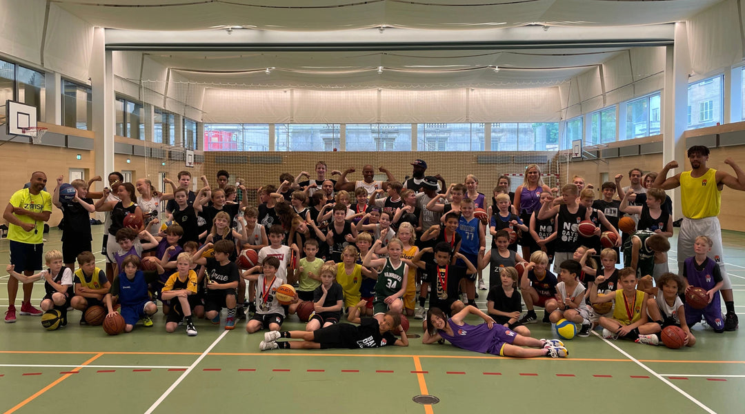 Large group of kids and coaches posing on court at a ZWISH basketball camp