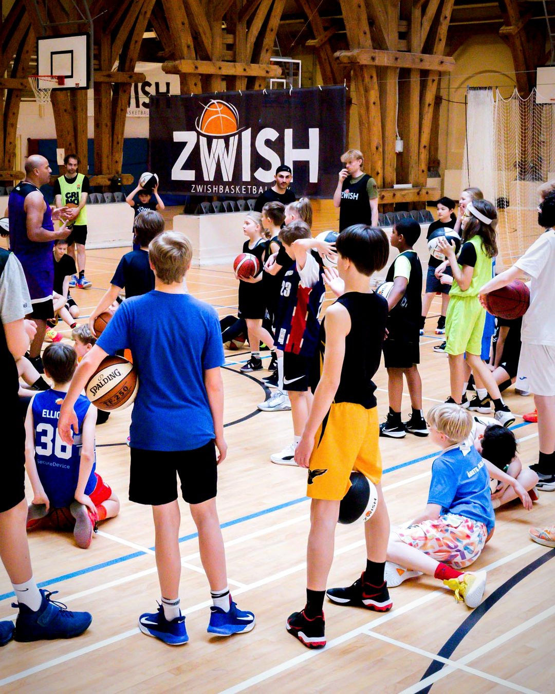 Kids and coaches at a ZWISH basketball camp in front of the ZWISH banner