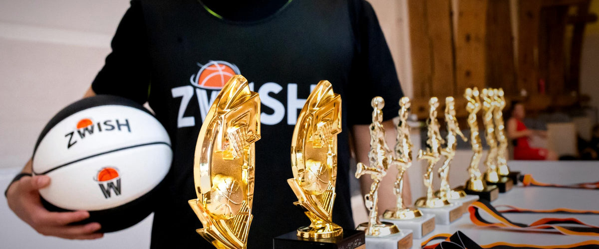 ZWISH coach holding a ZWISH basketball next to gold trophies