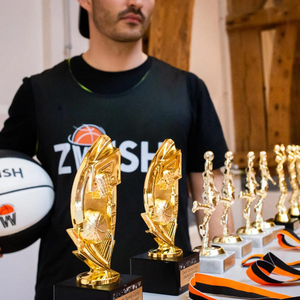 Coach in ZWISH shirt with gold trophies
